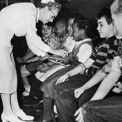 The hallmarks of the Polio Era include children on crutches, iron lungs, shuttered swimming pools and theaters warning movie-goers to not sit too close to one another. In 1955 The polio vaccine is developed by Dr. Jonas Salk and is approved for widespread use.