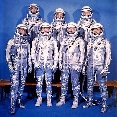 The original group of seven U.S. astronauts are selected by NASA for Project Mercury with a goal of manned spaceflight. The Mercury Seven are Scott Carpenter, Gordon Cooper, John Glenn, Gus Grissom, Wally Schirra, Alan Shepard, and Deke Slayton.