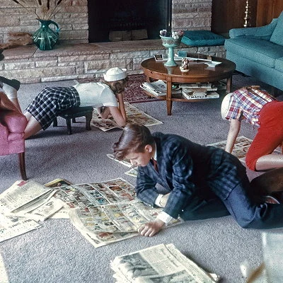 Children on the living room floor reading the Sunday paper 1960.
