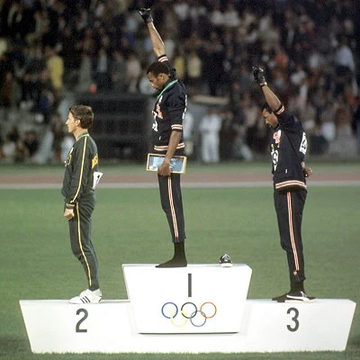 American athletes Tommie Smith and John Carlos raise their fists in the Black Power salute on the medal stand at the Summer Olympics in Mexico City.