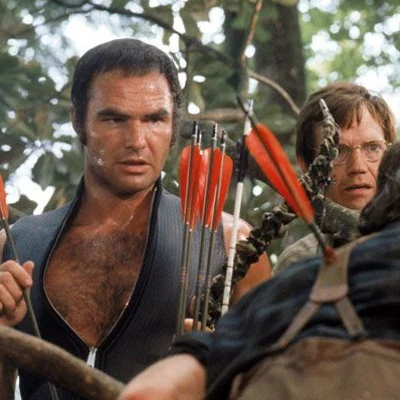 Burt Reynolds and Jon Voight star in the backwoods thriller Deliverance. Early in the film a memorable music scene depicts one of the men from Atlanta playing guitar together with a banjo playing country boy on the song "Dueling Banjos".