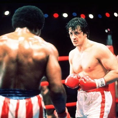 Sylvester Stallone writes and stars in the sports drama film Rocky. The hit movie goes on to spawn seven sequels.