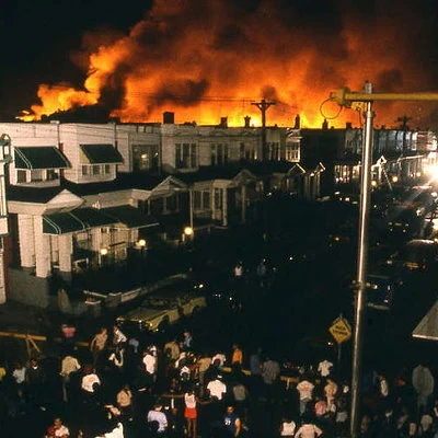 The Philadelphia Police bomb the house occupied by MOVE, a black separatist group. Following a standoff, the fire department lets the fire spread, destroying sixty homes and killing eleven people.